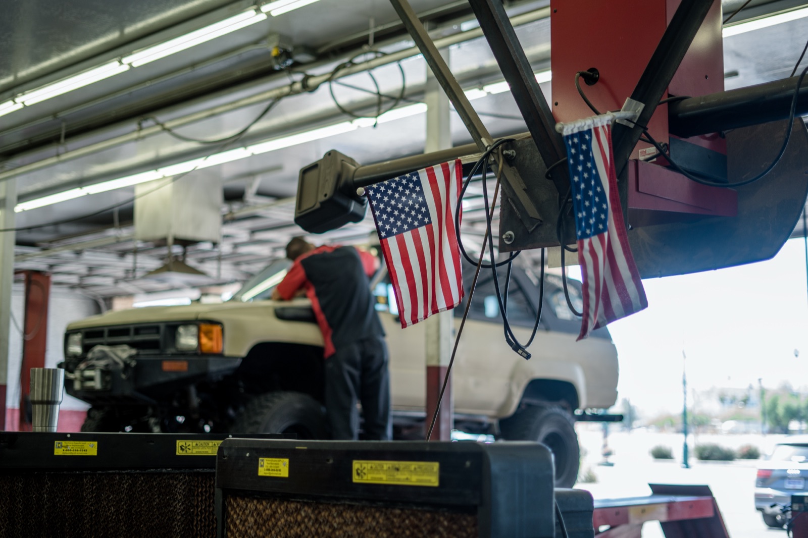 Truck on a lift under American flags inside a Network Automotive bay