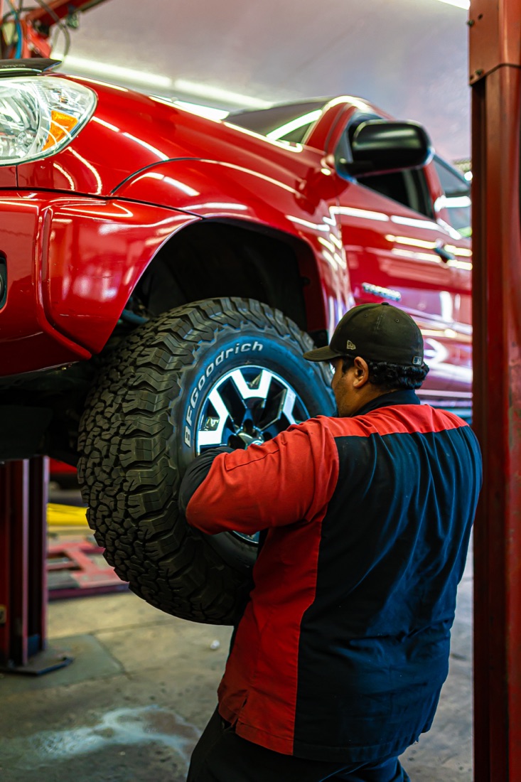 Technician working on the wheel of a lifted red truck